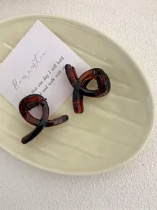 Detail shot of two brown tortoiseshell hair claws with a unique ribbon twist design