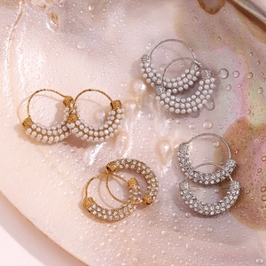 Macro detail of 18K gold and silver hoop earrings with pearls and crystals on shell