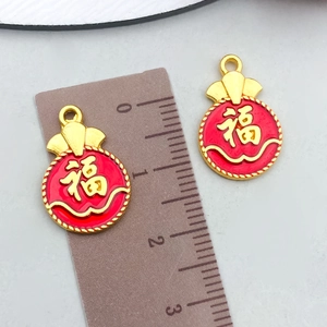 Detailed view of red and gold Fu bag pendants with a ruler showing the 2cm size