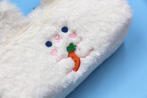 Macro shot of fluffy white plush pencil case featuring cute bear embroidery and heart detail