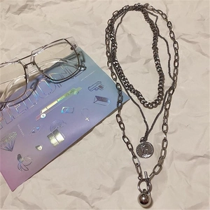 Three-layer silver metal necklace with coin pendant and toggle clasp on white paper