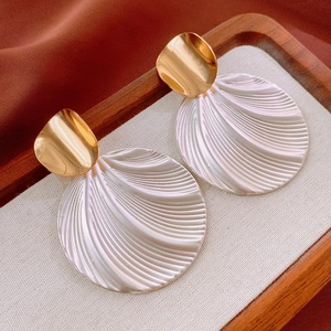 Macro detail of vintage gold curved earrings with pearlescent shell textured pendants