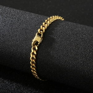 Detail shot of a golden Cuban link bracelet with high-gloss finish on a black stand