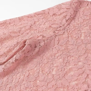 Macro shot of delicate pink lace fabric detail showing floral patterns and stitching