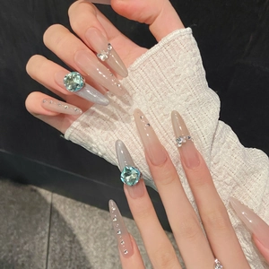 Close-up detail showing grey cat-eye press-on nails adorned with luxury K9 blue crystals