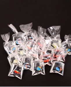 Détail macro de mini poissons tropicaux en résine dans de petits sacs d'eau pour bijoux DIY