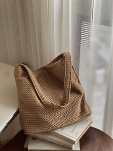 Detailed view of the V-shaped woven texture and simple tag on a beige knit shoulder bag