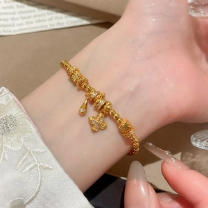 Detailed close-up of 24K gold plated clover charm bracelet worn on a woman's wrist