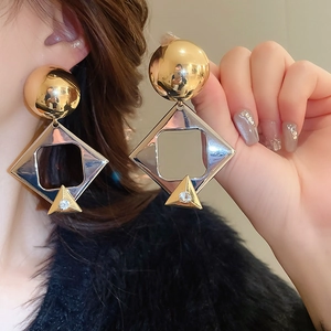 Detail of geometric gold earrings with spherical, square and rhinestone triangle charms
