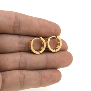 Close-up of small 18K gold-plated huggie hoop earrings with vintage engraved textures