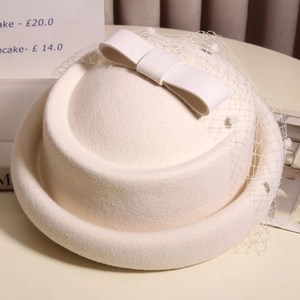 Detail of white wool fascinator hat with elegant mesh veil and vintage bow decoration