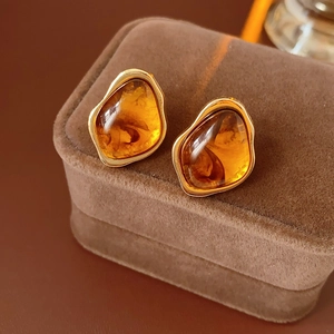 Close-up of vintage gold geometric earrings with amber resin stones on a velvet box