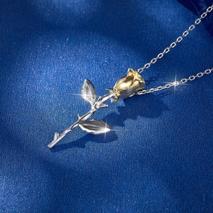 Detail of S925 silver two-tone rose necklace pendant on a blue textured background