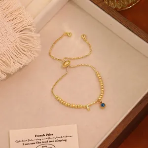 Dettaglio del bracciale a sfere dorate regolabile con occhio greco e lettera F di strass