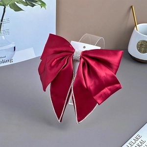 Close-up of red velvet bow hair clip with rhinestone edges and crystal fringe detail