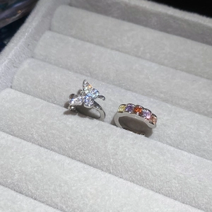 Detail view of crystal butterfly ring and multi-color gemstone band in gray velvet box