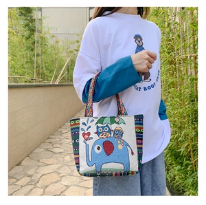 Detailed view of canvas handbag featuring cartoon elephant and boho woven straps