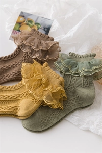 Flat lay of knit cotton girls' socks in brown, yellow, and green with delicate lace cuffs