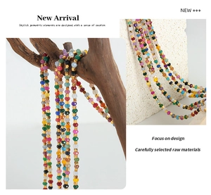 Detailed close-up of colorful tourmaline beaded necklace on white textured stone surface