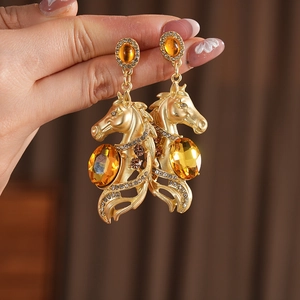 Nahaufnahme von Vintage-Pferdeohrringen in Gold mit Bernstein-Steinen und Strasssteinen