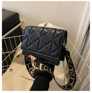 Close-up of black quilted crossbody bag with a wide printed strap and PU leather texture