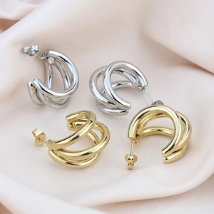 Macro shot of gold and silver triple-layered C-shaped earrings on soft silk background