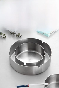 Nesting stainless steel ashtrays in large and small sizes with brushed finish on white desk