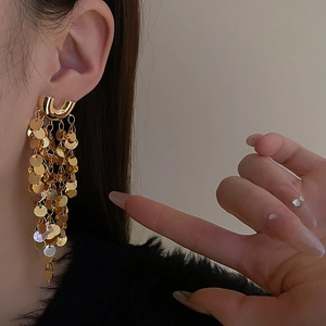Gros plan de boucles d'oreilles pendantes à sequins dorés portées par un mannequin