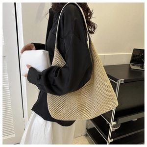 Detail view of a beige straw woven shoulder bag with a casual summer beach aesthetic