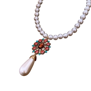 Elegant vintage pearl necklace with a teardrop pearl and gemstone pendant on white background