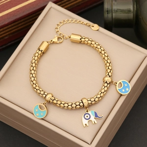 Bracciale dorato con ciondoli elefante e luna stella su fodera di portagioie beige chiaro