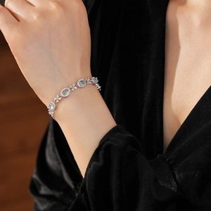 Macro detail of silver floral bracelet with light blue oval gemstones and zircon accents
