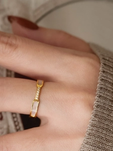 Detail of gold titanium ring featuring white mother-of-pearl inlay and micro-zirconia stones