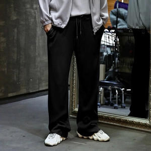 Close-up of men's black vertical striped trousers showing texture and drawstring waist