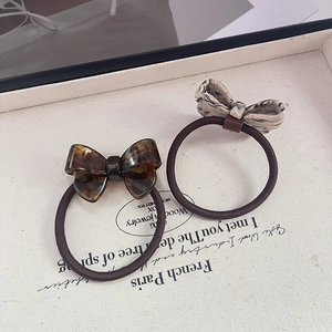Detail showing two handmade acetate bow hair ties with tortoiseshell and marble patterns