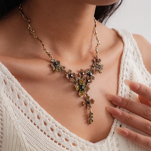 Close-up of vintage Y-shaped floral necklace with amber and olive gems on model
