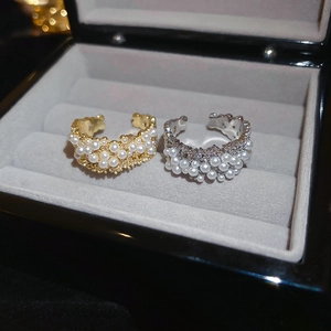 Detailed macro view of gold and silver plated pearl rings on a grey velvet jewelry box