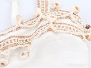 Detail of white wrinkled fabric with beige crochet lace and decorative round beads