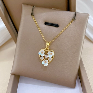 Detailed close-up of a heart pendant with white flowers and crystals on a gold chain