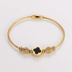Detail of gold twisted wire cable bracelet featuring a black clover inlay design