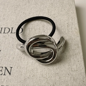 Minimalist silver irregular knotted metal hair tie with black elastic cord on book