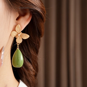 Gros plan sur des boucles d'oreilles papillon dorées vintage avec goutte en résine verte