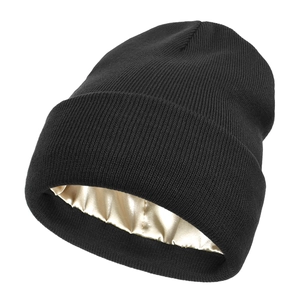 Detail of black knit beanie featuring a smooth champagne gold satin lining for hair care