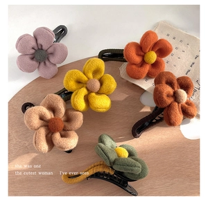 Detailed overhead shot of six felt flower hair clips in various colors on a wooden tray