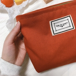 Close-up of orange houndstooth canvas pouch with Time to Party patch and top zipper