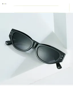 Detail of black cat-eye sunglasses with silver rivets on a white geometric stand