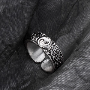 Close-up of vintage silver alloy ring with Yin Yang symbol and textured wave relief