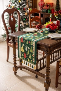 Christmas table runner with green jacquard trees and tassels on a rustic wooden table