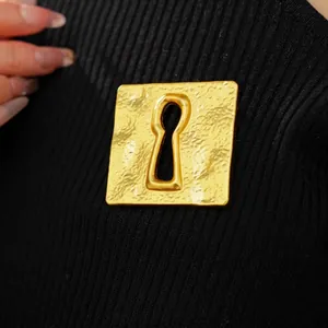 Vintage gold square brooch with keyhole cutout and hammered metal texture on black knit