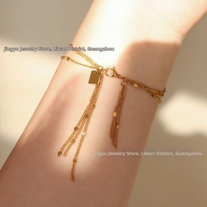 Detail of a 18K gold plated multi-layer tassel bracelet with polished tag and lobster clasp